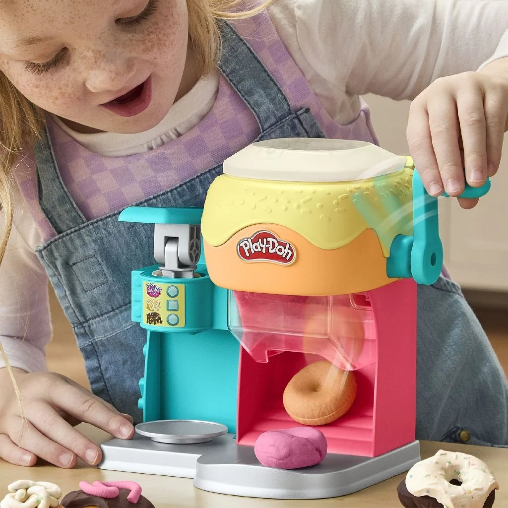 Una niña usa una máquina Play-Doh para hacer donas.