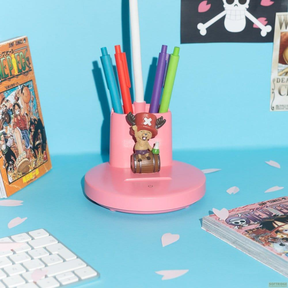 Escritorio rosa con portalápices rosa, bolígrafos, una figura y libros de One Piece.