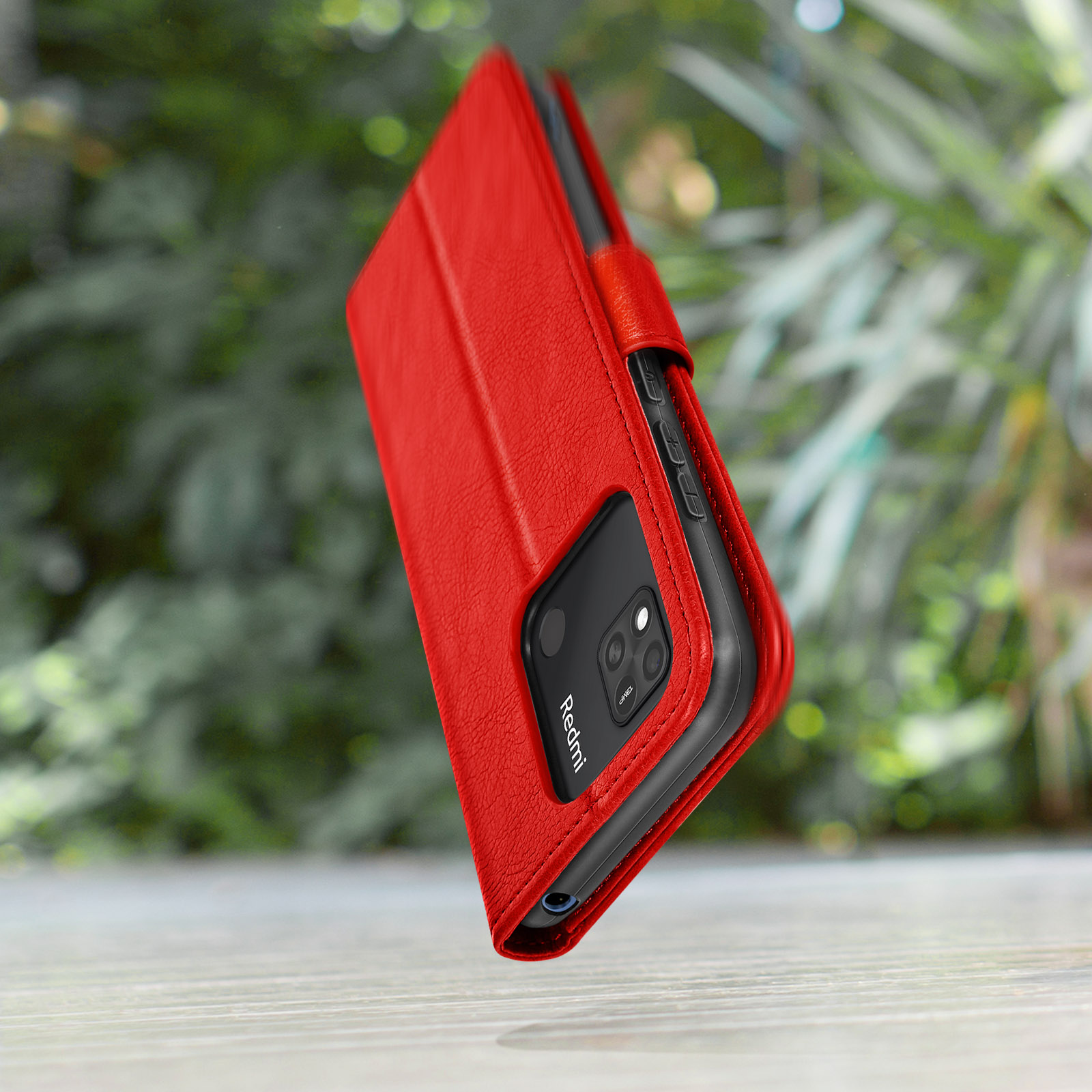 Rotes Handycover im Freien auf Holz, mit verschwommenem grünen Hintergrund.
