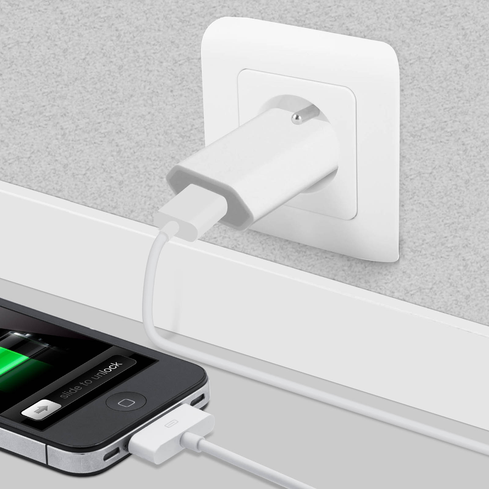 An iPhone is charging via a white cable connected to a white wall socket.
