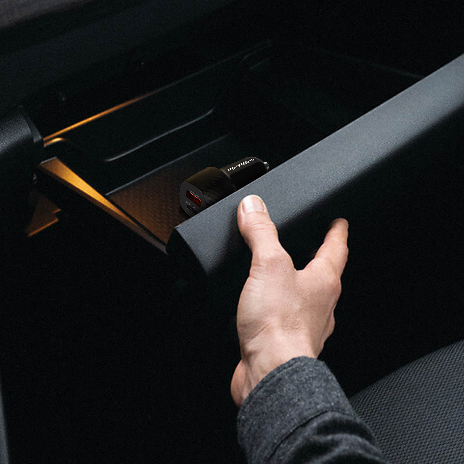 Mano raggiunge vano portaoggetti auto con caricatore USB nero.