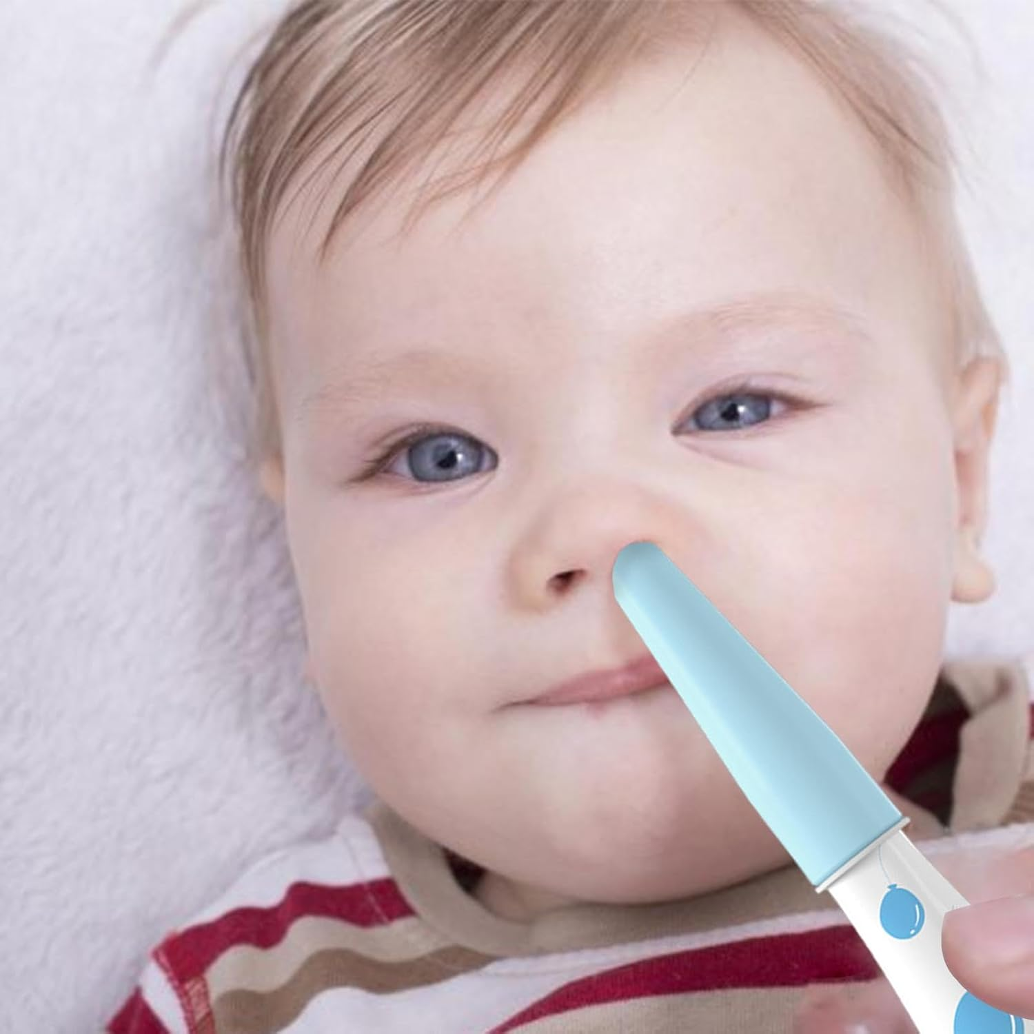 Ein Baby mit blauen Augen und blonden Haaren, dem ein blauer Nasensauger an die Nase gehalten wird.