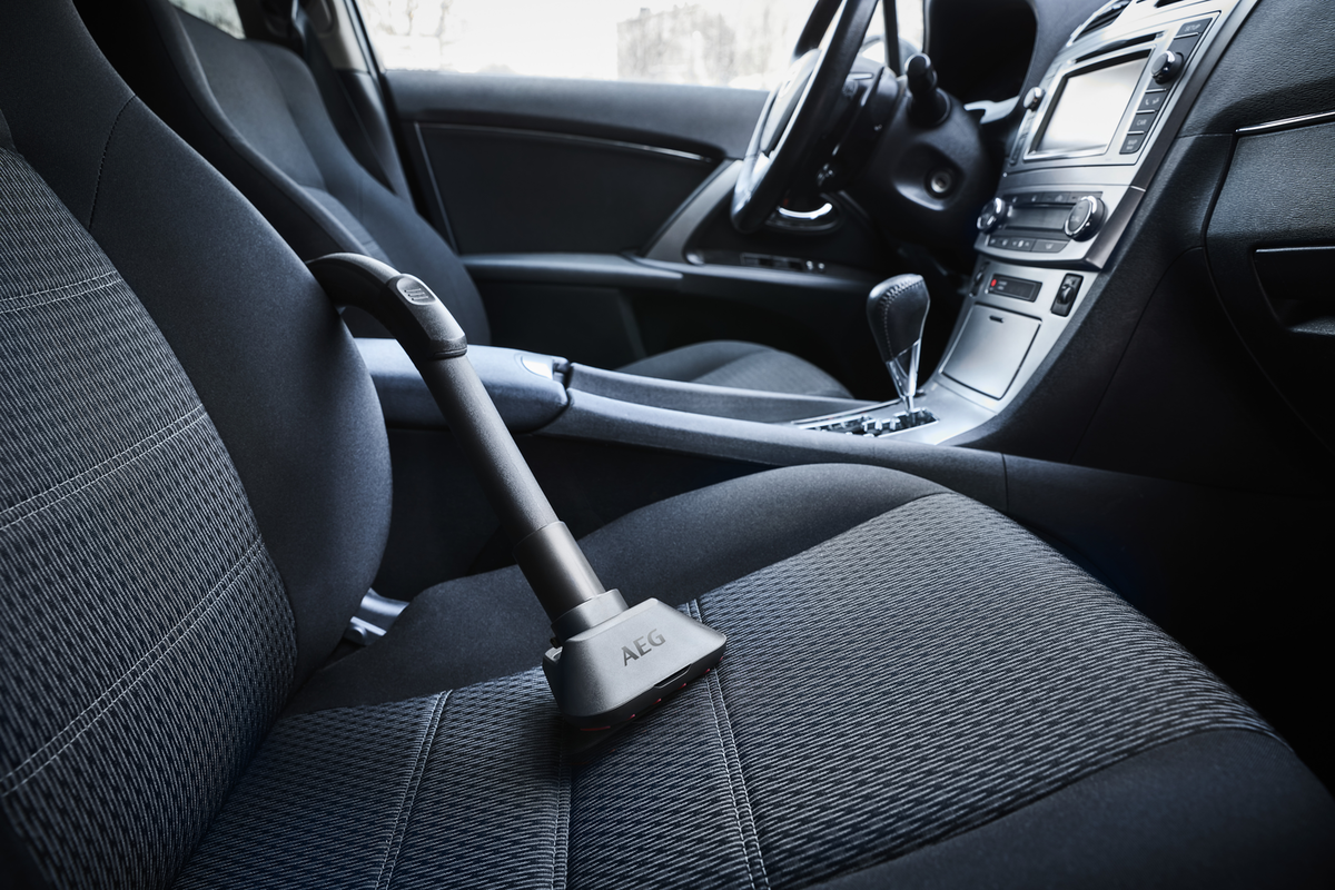 Ein AEG-Handstaubsauger auf dem Sitz eines Autos.