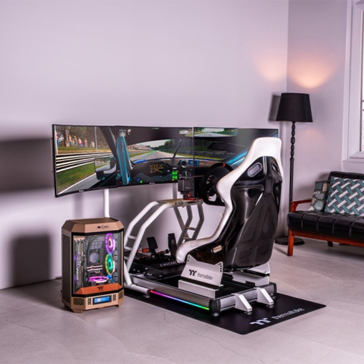 Una configuración de simulador de carreras con pantalla triple, silla gaming, PC y lámpara.