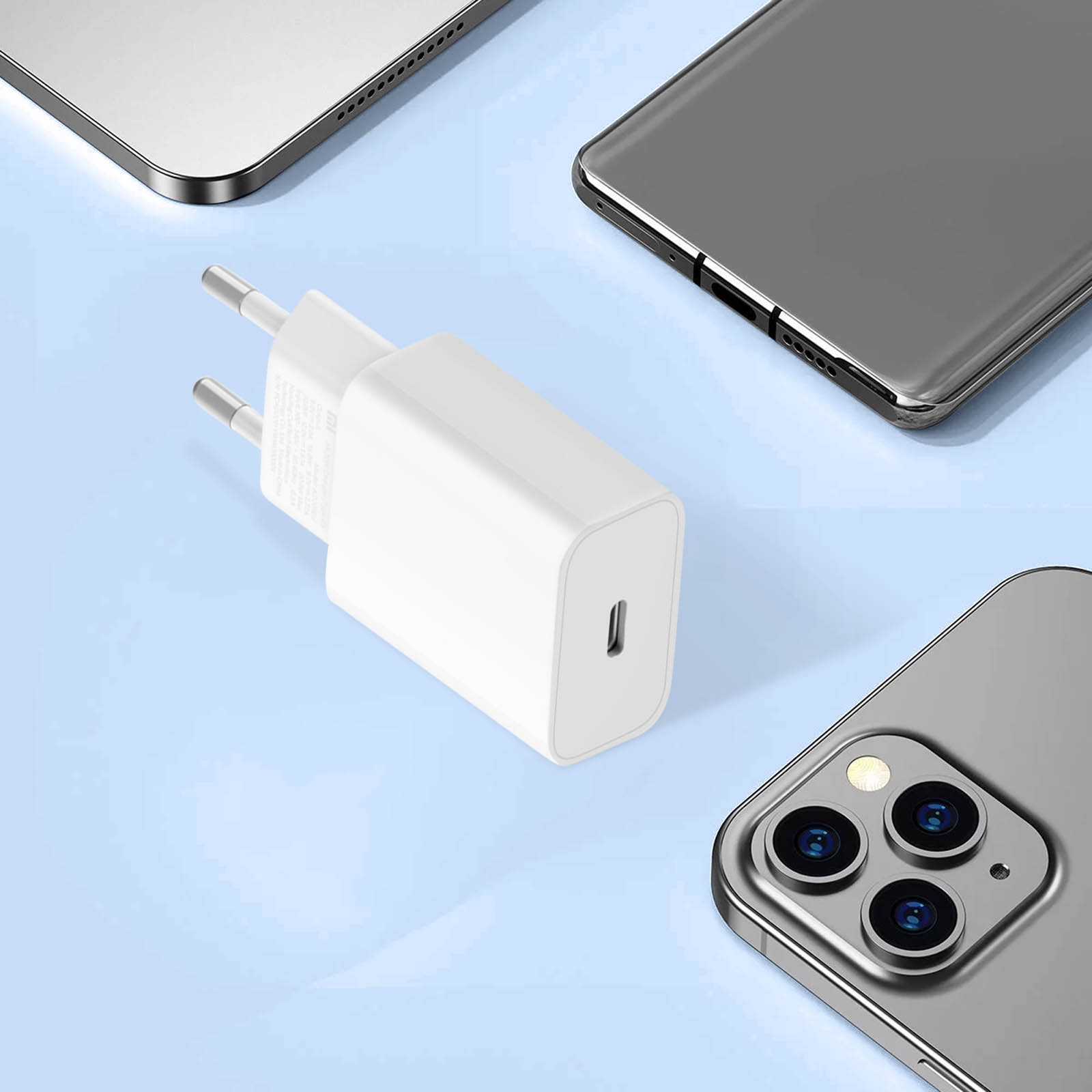 Un chargeur USB-C blanc et des parties de trois smartphones sur fond bleu clair.