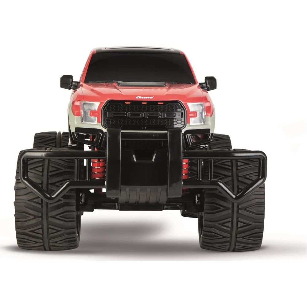Un camión de juguete rojo RC Ford Raptor con parachoques negros y neumáticos grandes.