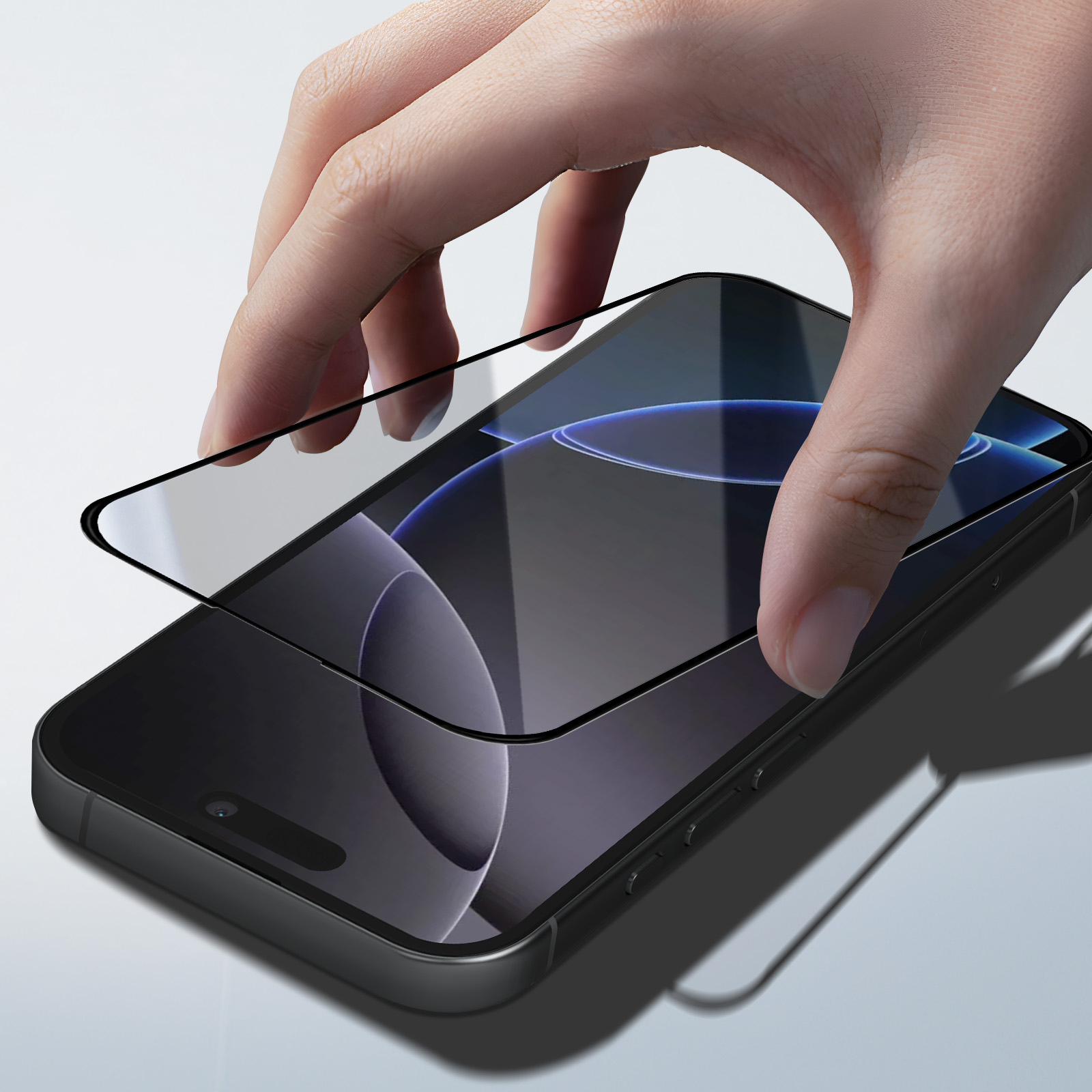 Una mano posiziona una protezione per lo schermo su uno smartphone scuro.