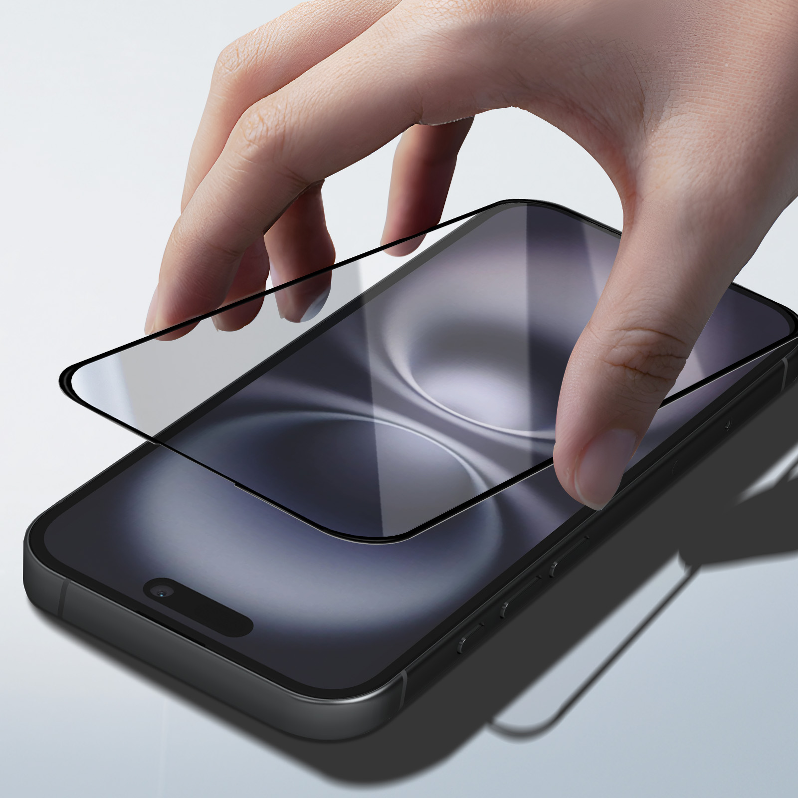 Una mano posiziona una protezione per lo schermo trasparente su uno smartphone scuro.
