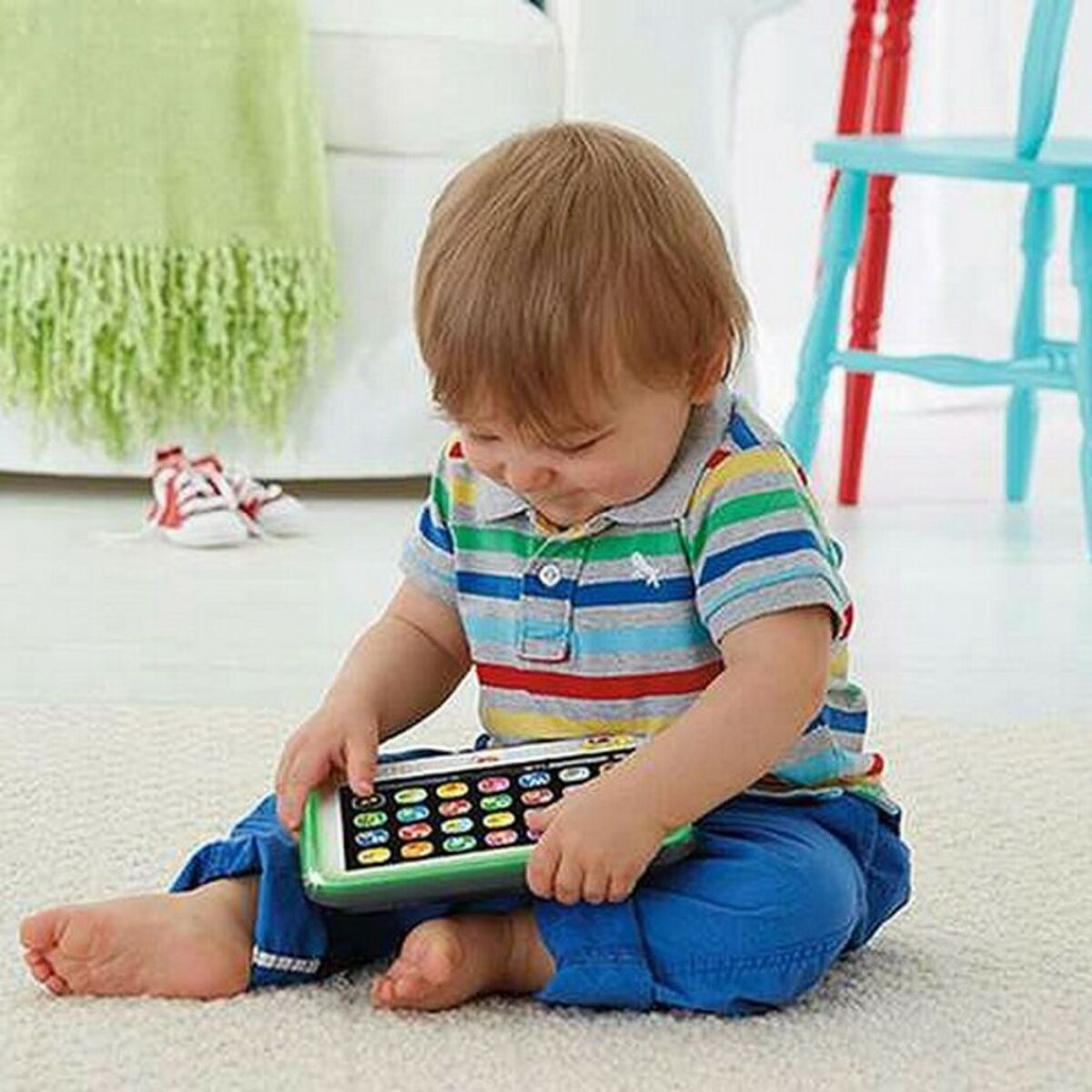 Un niño pequeño se sienta en una alfombra jugando con un teléfono de juguete.