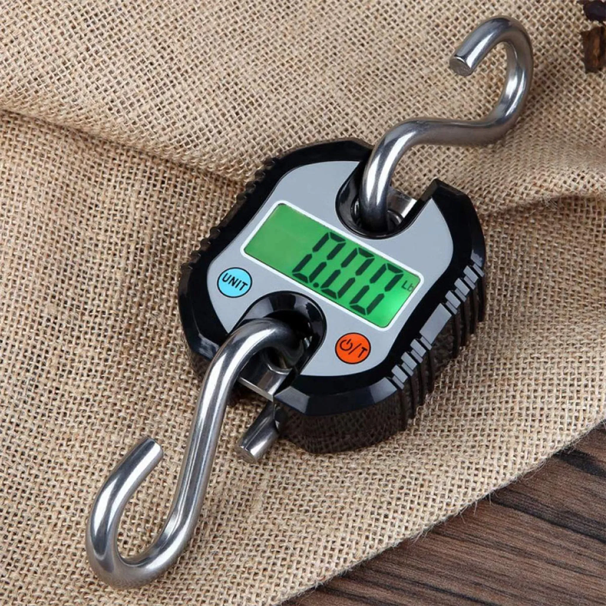Digitale Hängewaage mit grünem LCD-Display und Haken auf Jute-Unterlage.