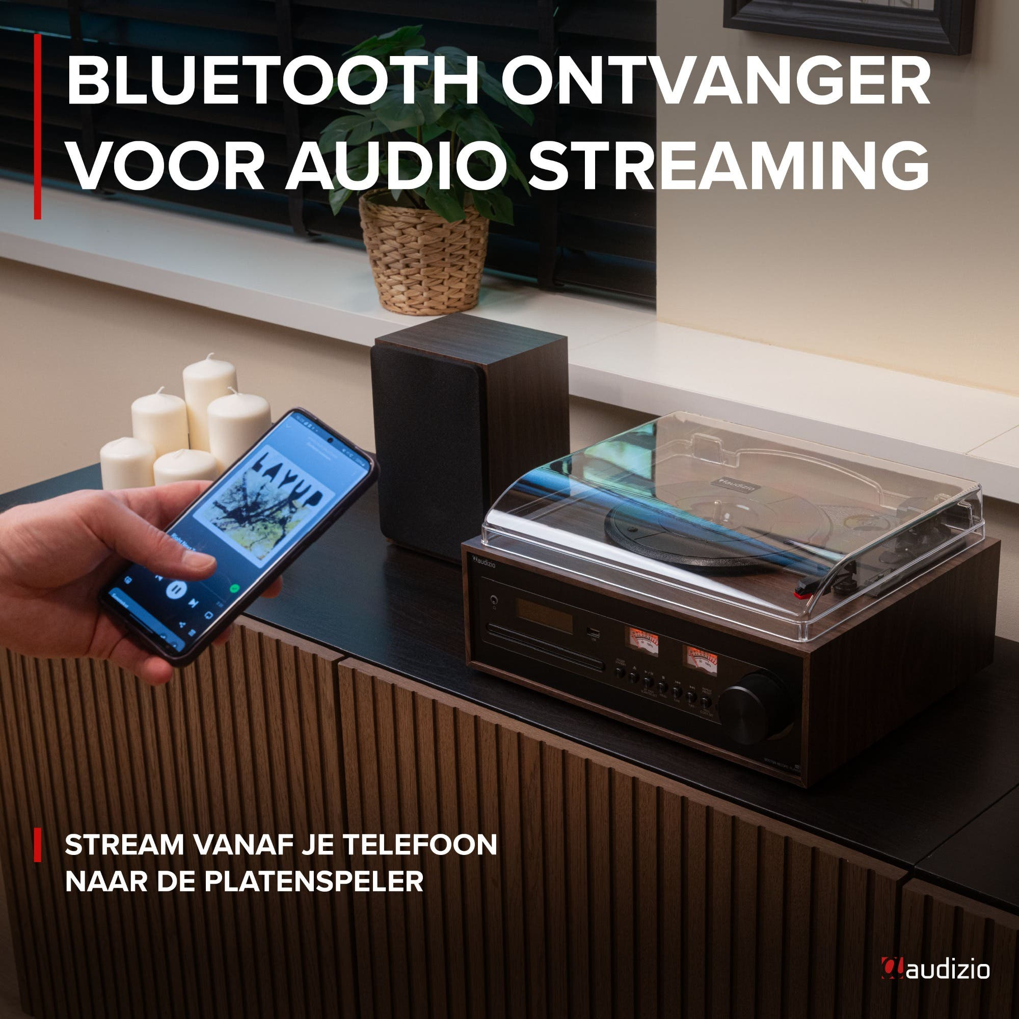 Un smartphone diffuse de la musique vers un tourne-disque avec enceinte et bougies.