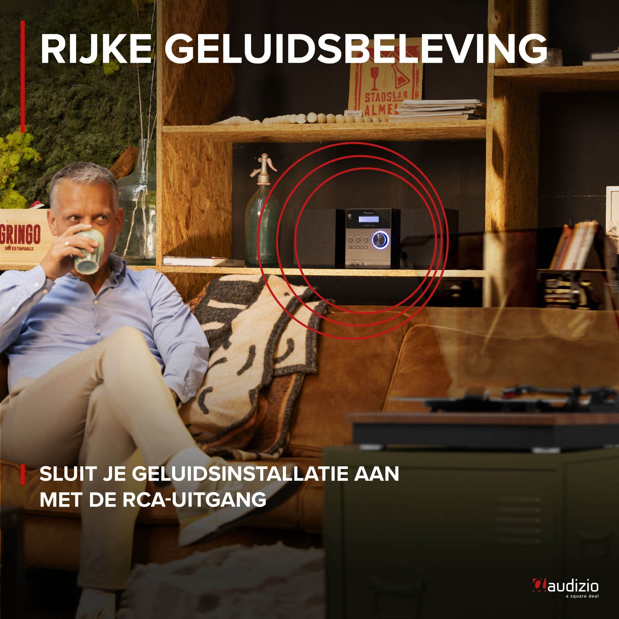 Man drinks from mug near shelves with stereo and text. RCA output.