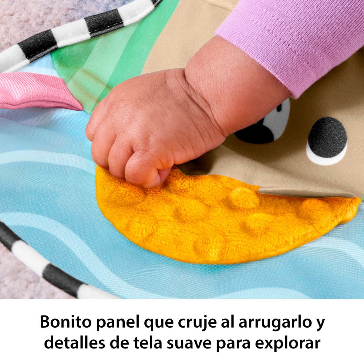 Mano de bebé toca un panel de tela amarillo que cruje en una alfombra de juego.