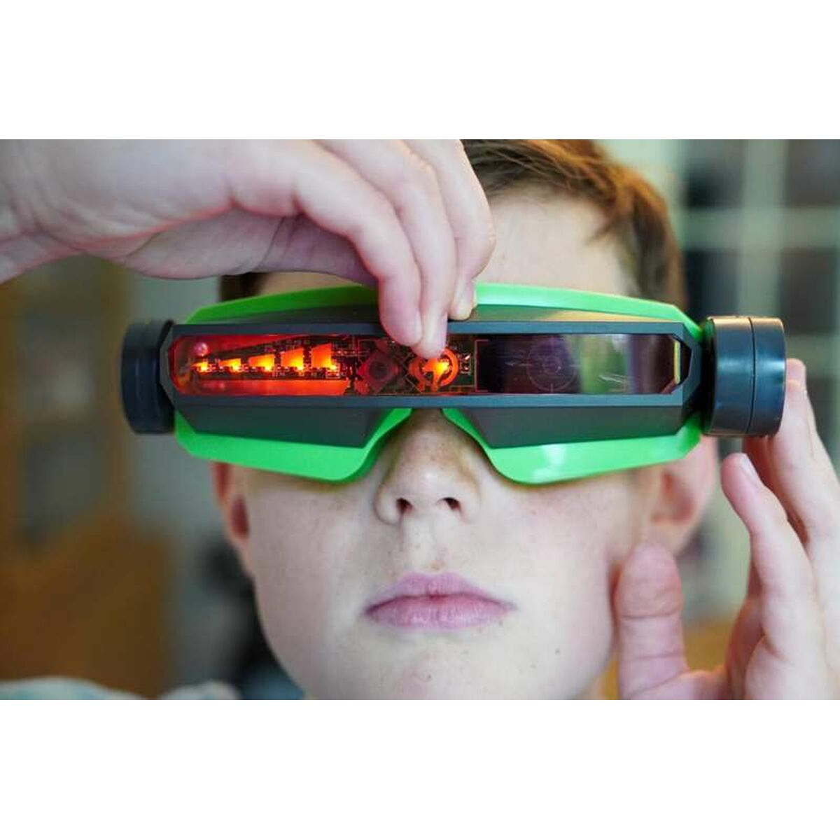 Un niño lleva gafas verdes con luces rojas dentro.