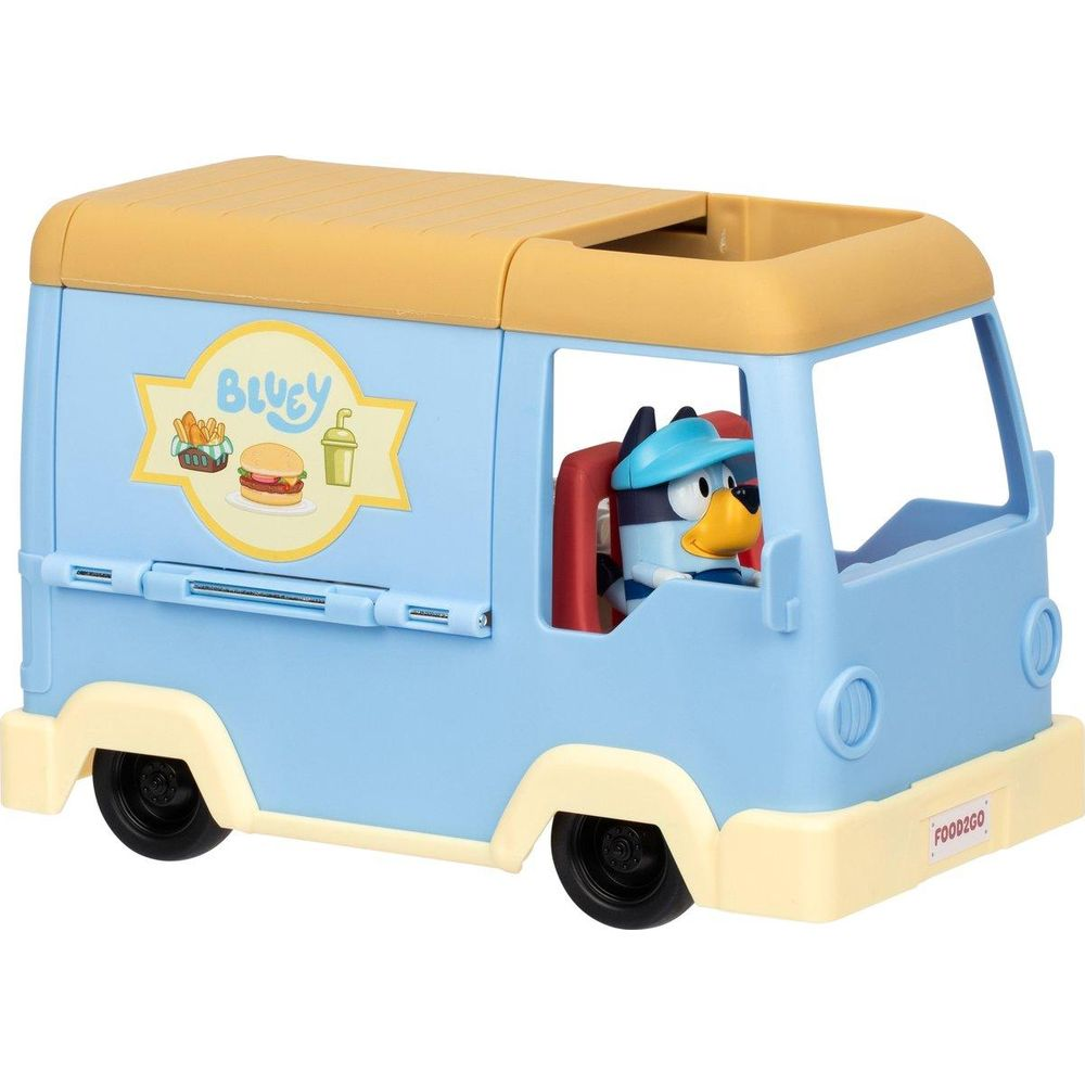 Camión de comida de juguete azul con techo amarillo. Un perro está al volante.
