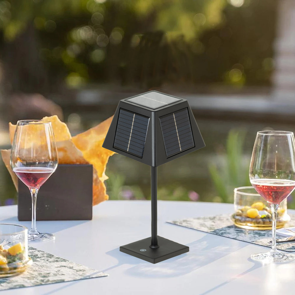 Un supporto per lampada da tavolo solare nero con bicchieri e snack su un tavolo bianco all'aperto.