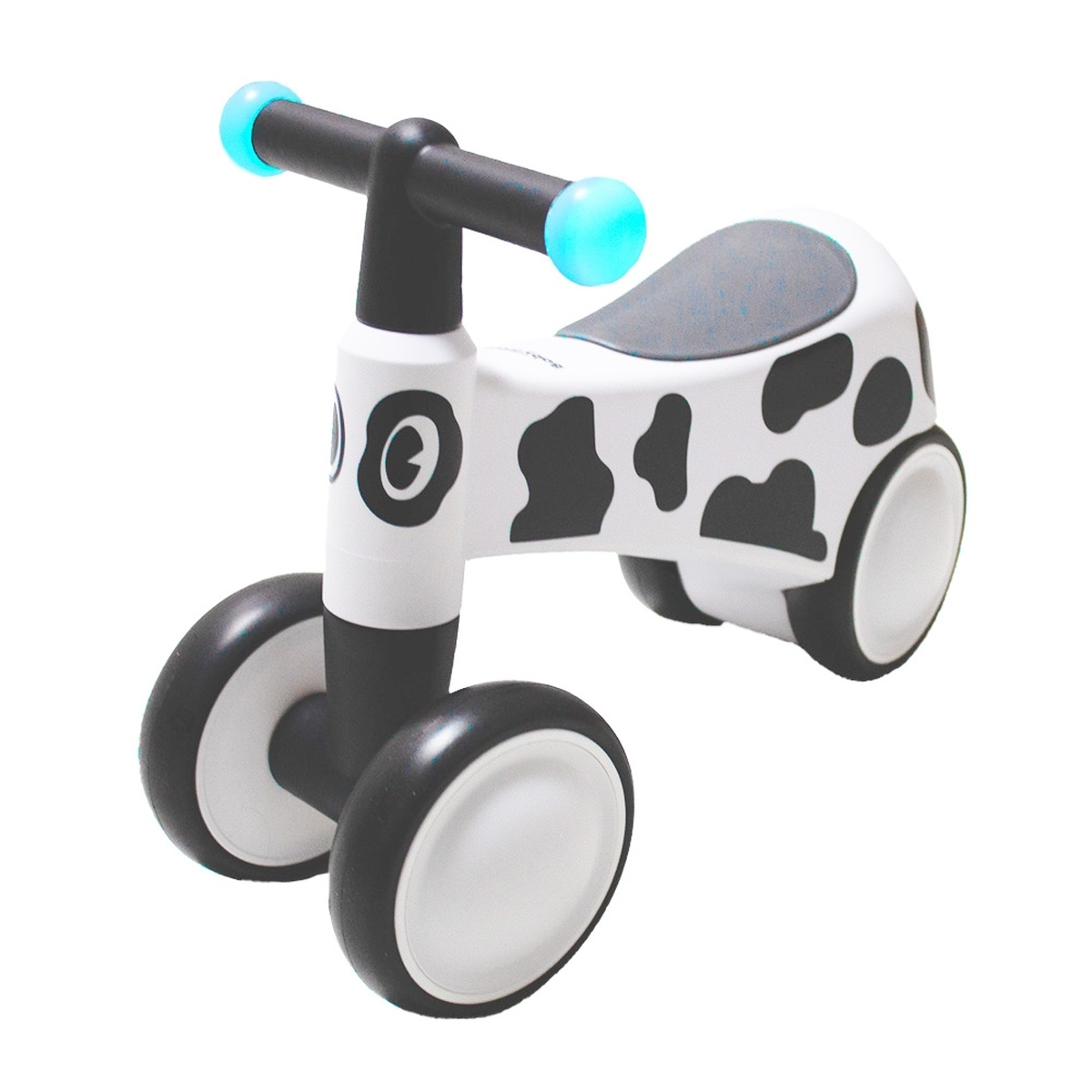 Ein weißes Kinderfahrrad mit schwarzen Kuhflecken und blauen Lichtern am Lenker.