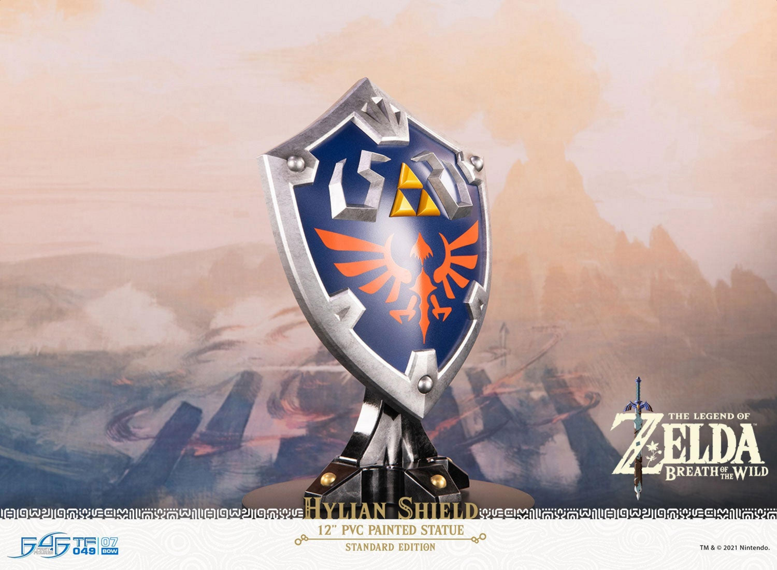 Hylian Schild Statue mit Triforce und Vogel-Symbol vor einer Bergkulisse.