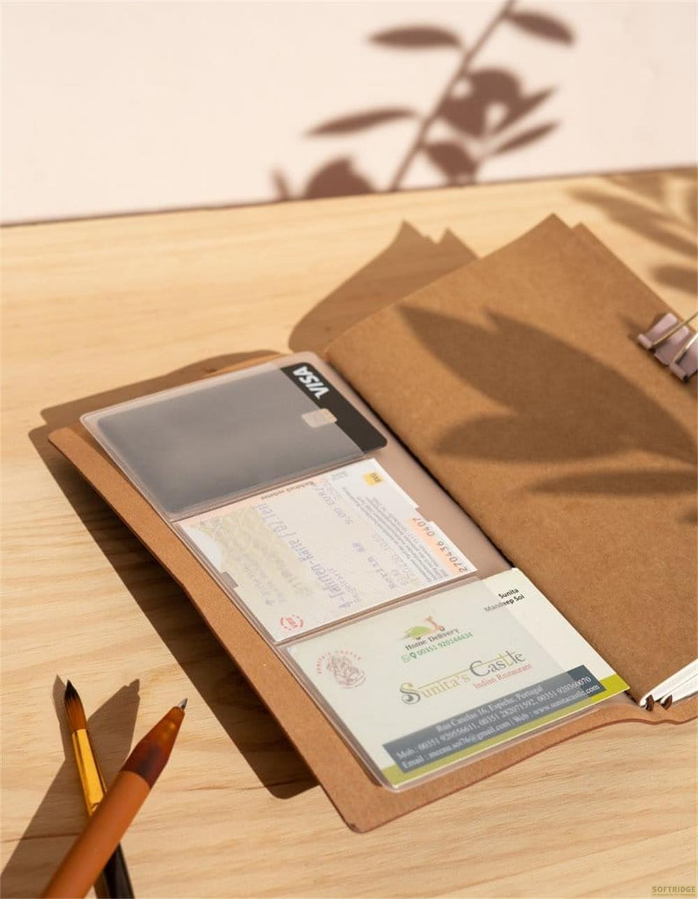 Un cuaderno marrón con una tarjeta VISA, un billete de viaje y una tarjeta de visita dentro.
