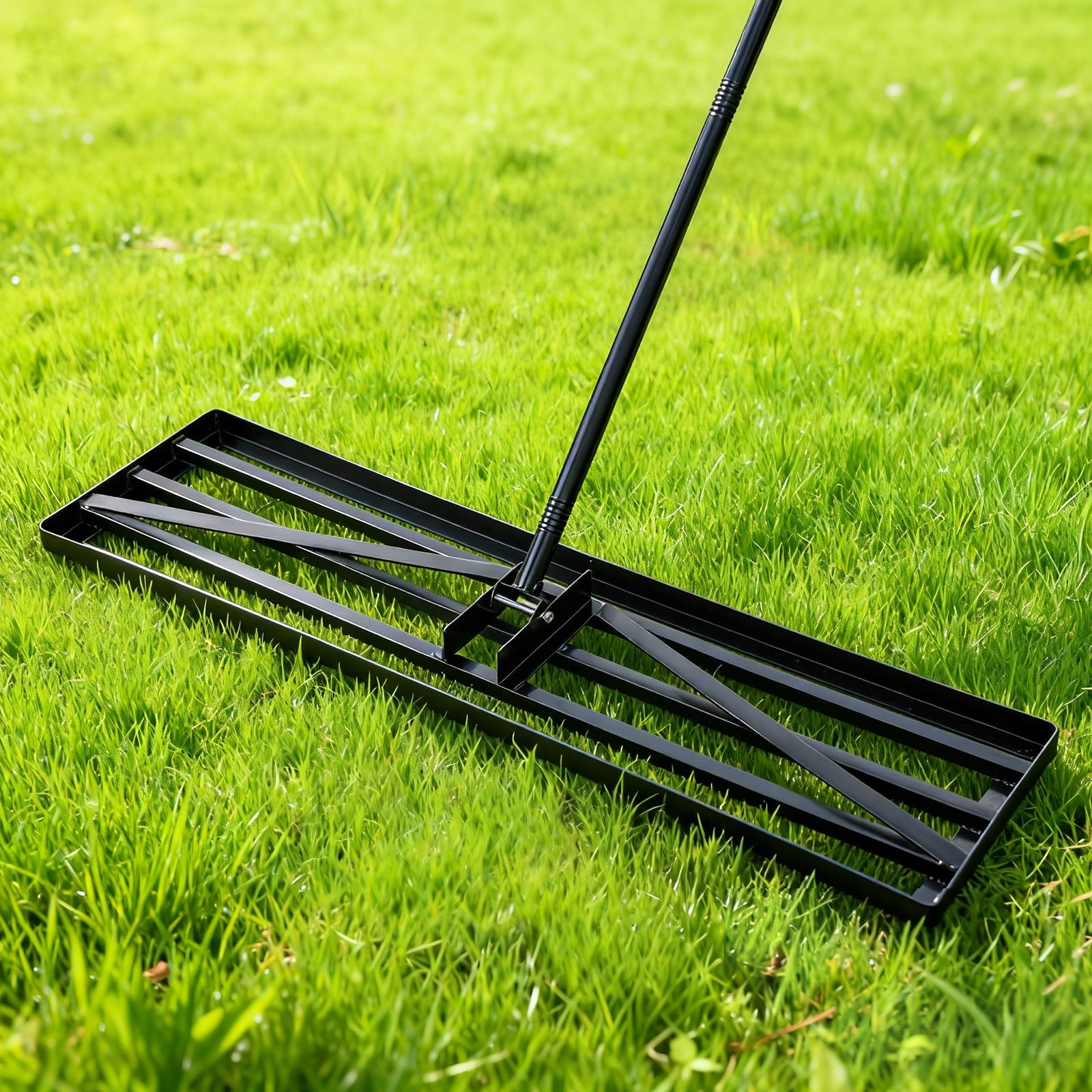 Ein schwarzer Rasenlüfter liegt auf sattgrünem Gras.