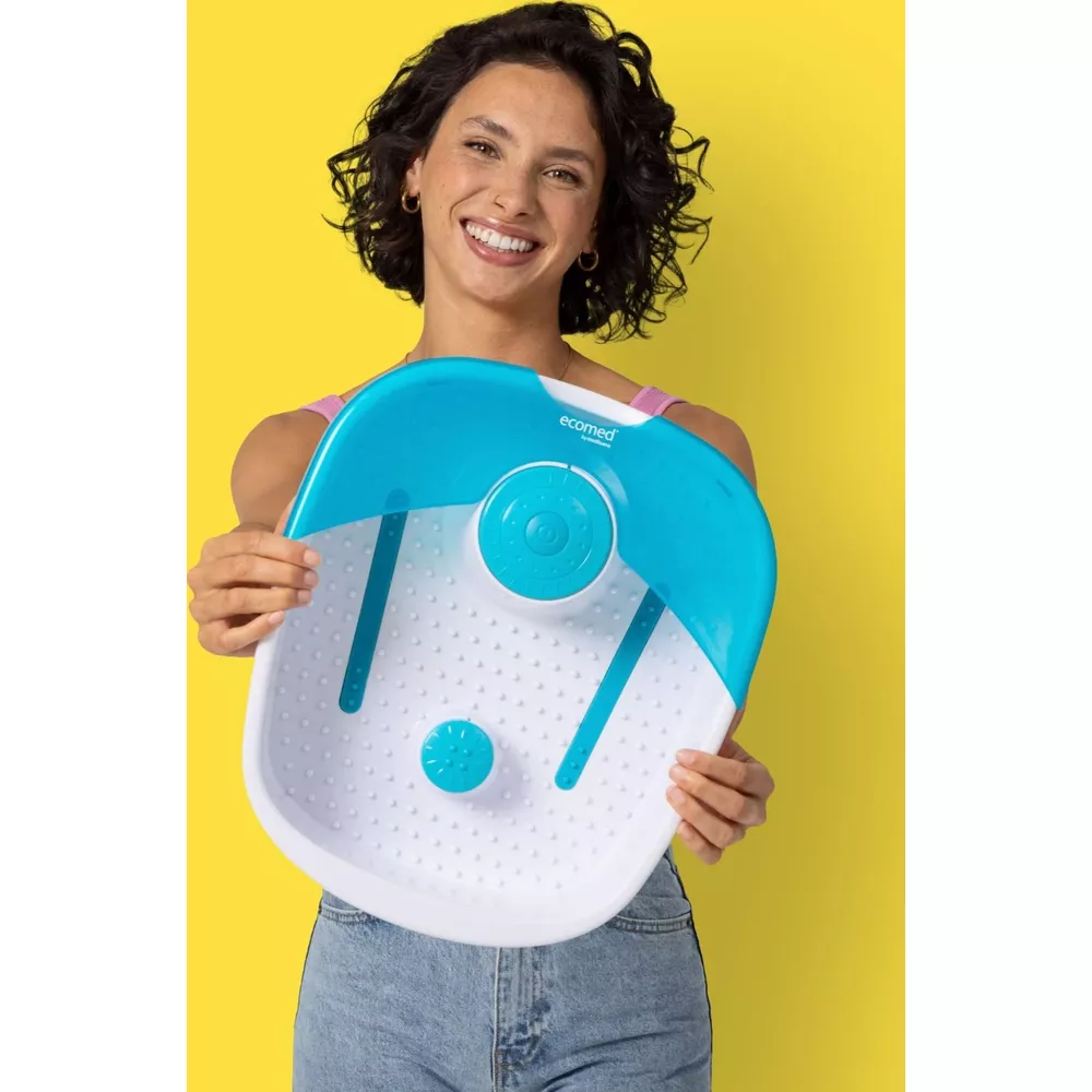 Donna sorridente tiene una pediluvio blu e bianca con funzioni a bolle e massaggio.