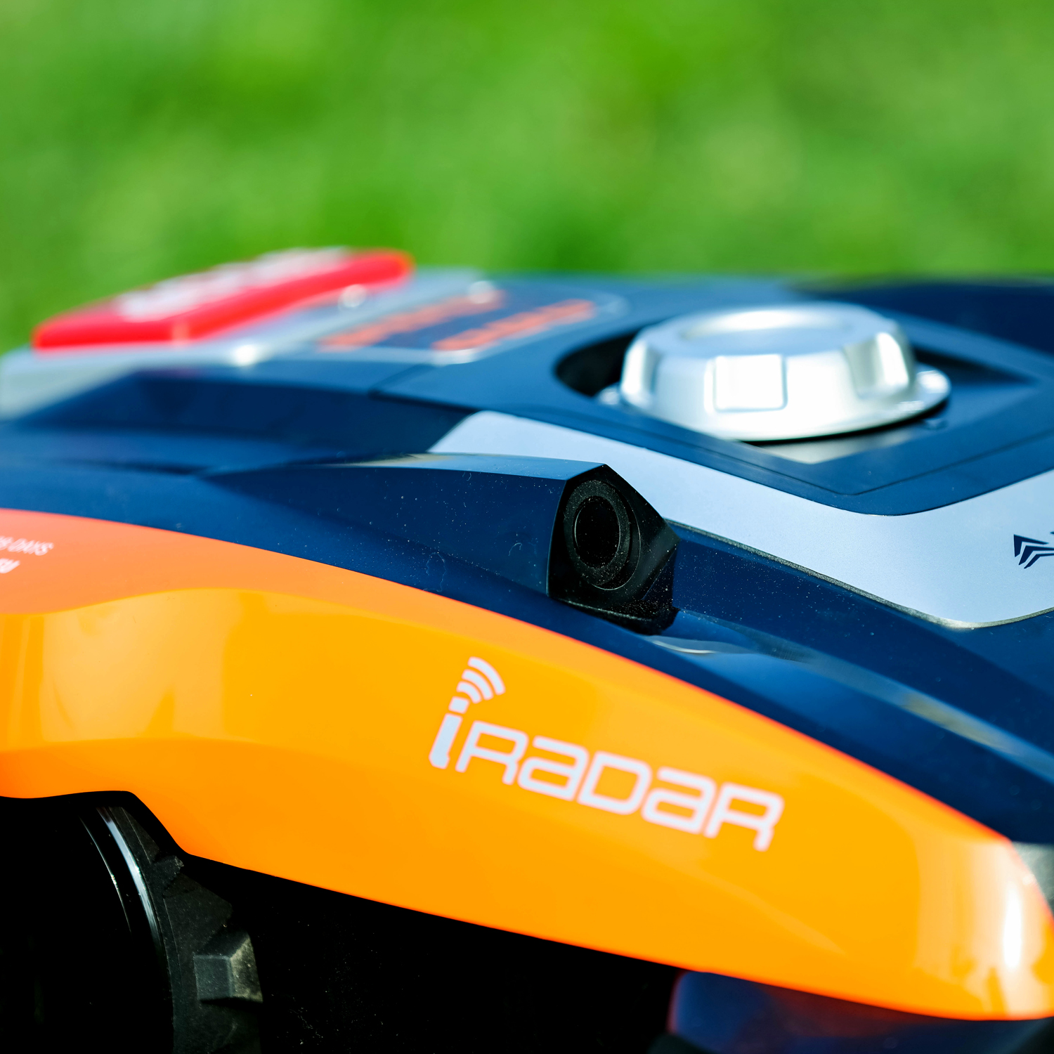 Ein blauer und oranger Roboter-Rasenmäher mit dem Wort 'iRadar' auf dem Gras.