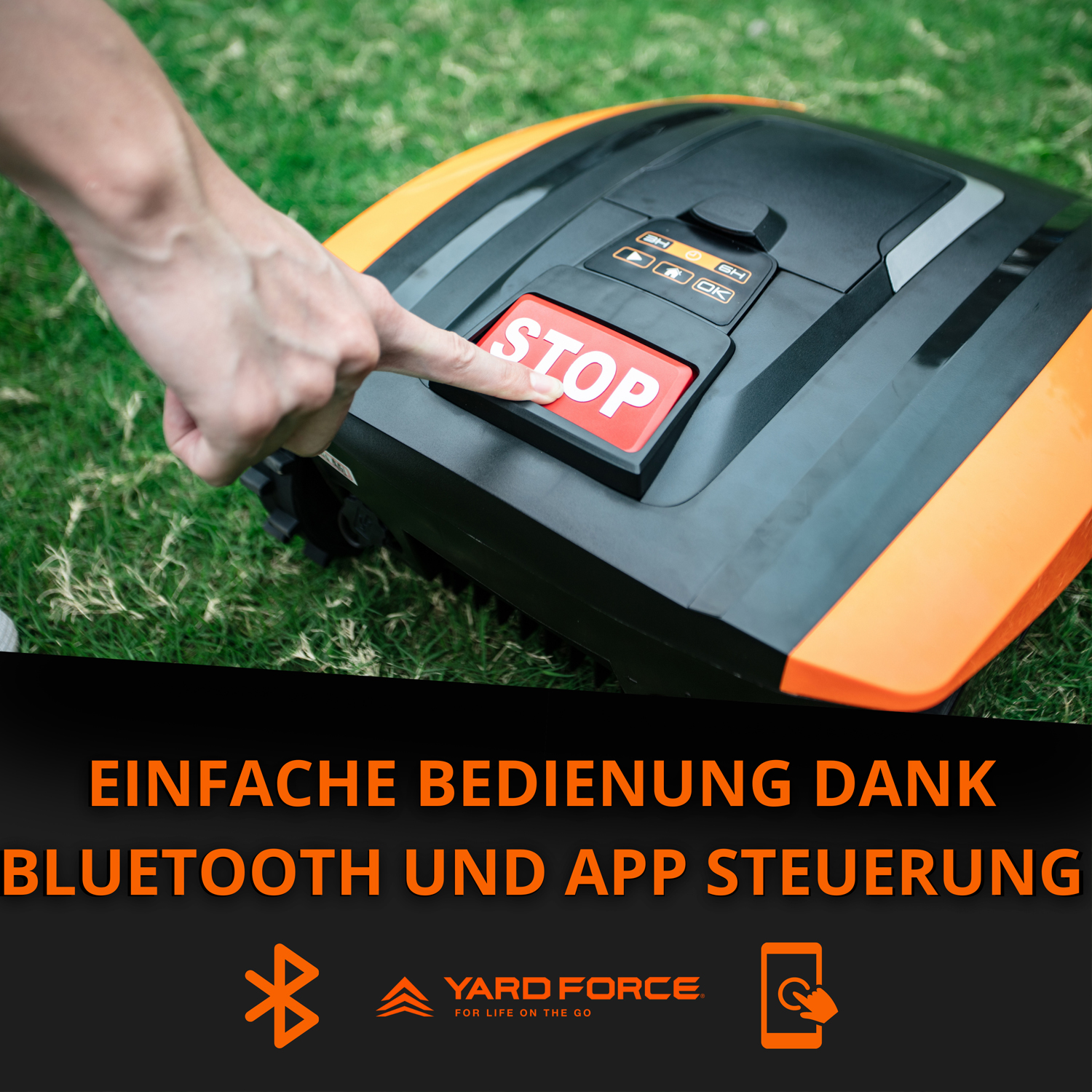 Ein Finger drückt auf den roten STOP-Knopf eines Mähroboters im Gras.
