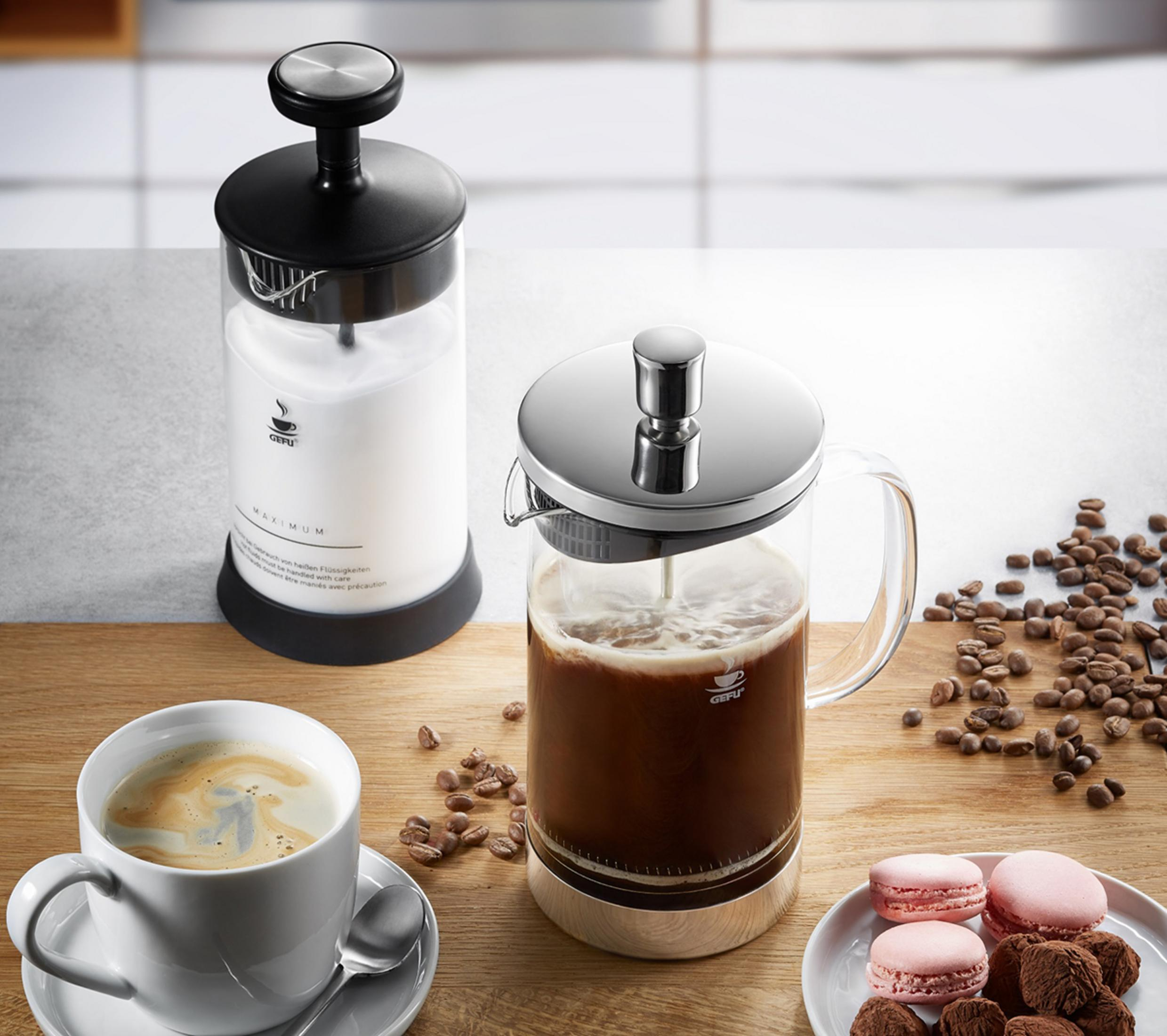 Kaffeebereiter mit Kaffee, Milchaufschäumer, Bohnen und Macarons.