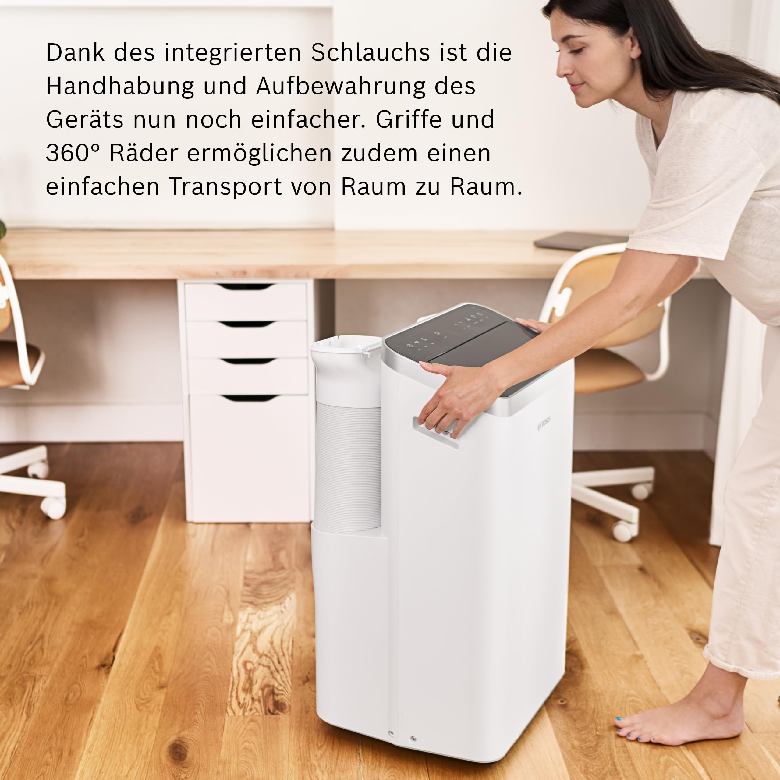 Een vrouw verplaatst een wit airconditioningsapparaat op een houten vloer.