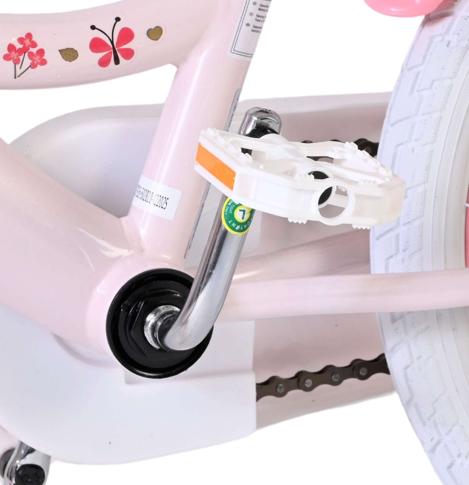 Nahaufnahme eines rosafarbenen Fahrradrahmens mit weißen Pedalen, einer silbernen Kurbel und einer Kette.
