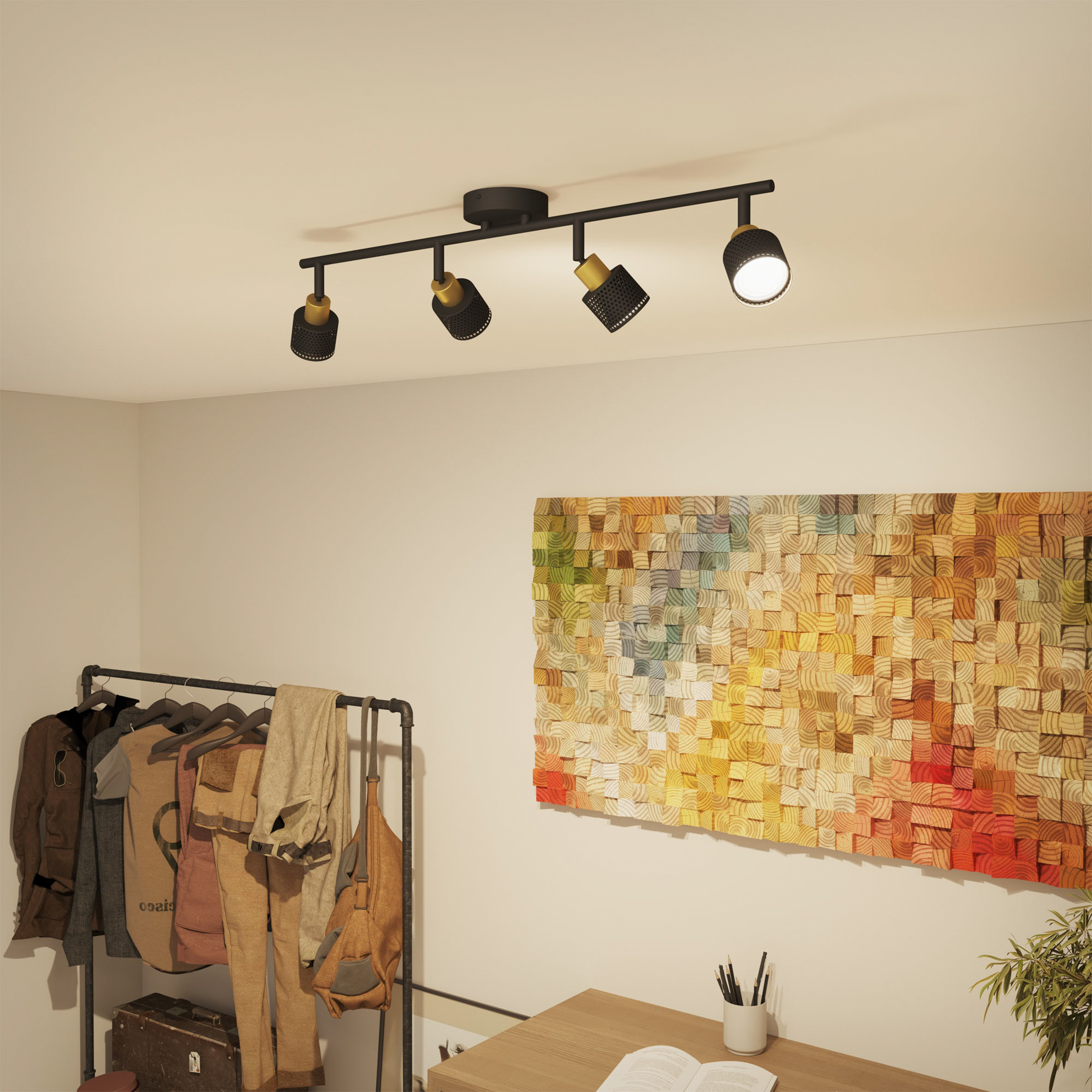 Ein moderner Deckenstrahler mit vier Spots über Kleiderständer und Kunstwerk.