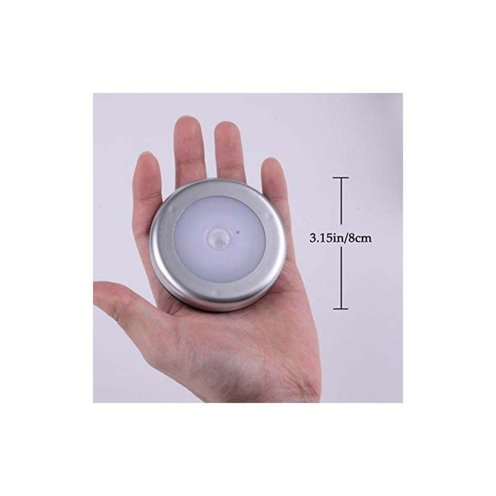 Eine Hand hält eine kleine, runde silberne Lampe mit weißem Licht.