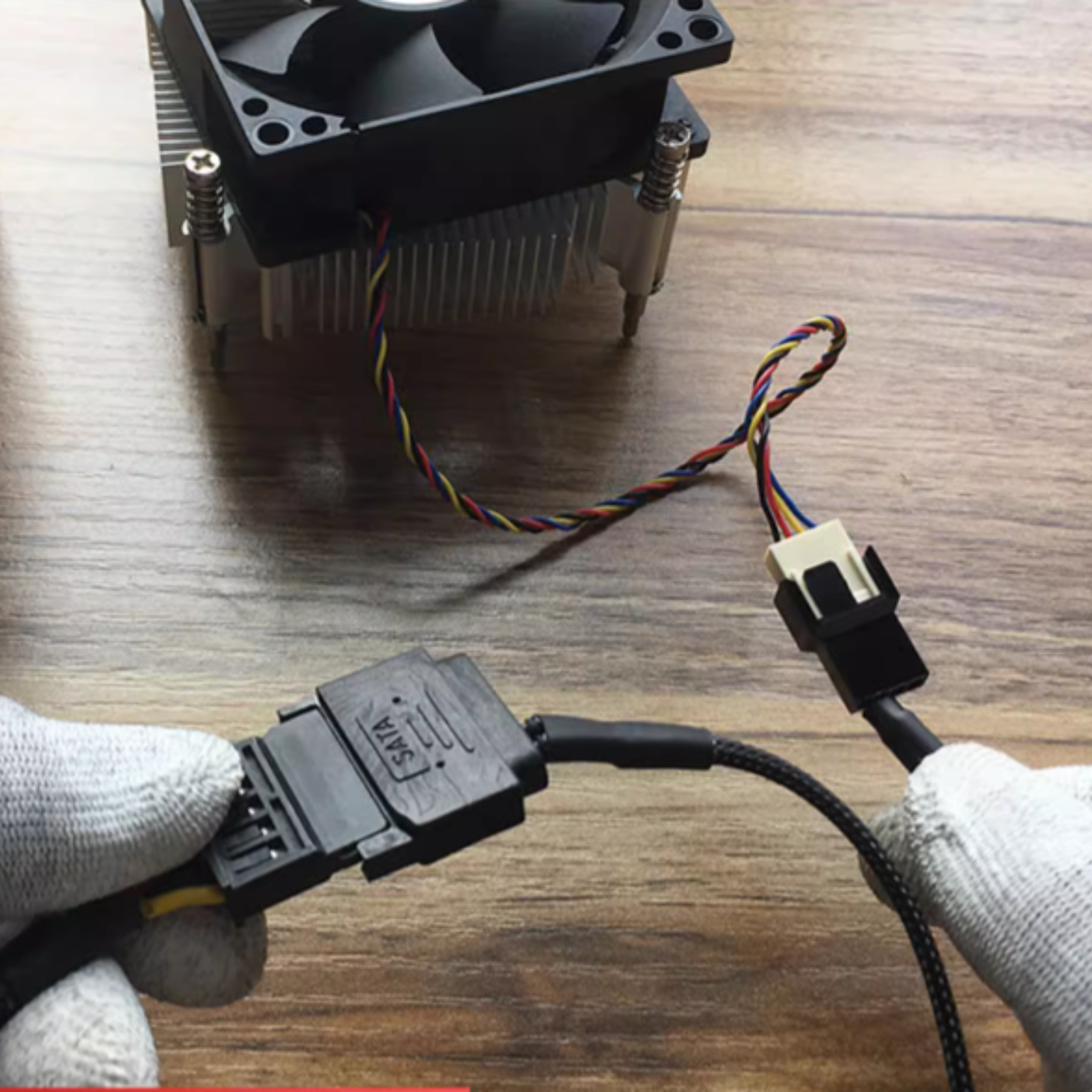 Hände in weißen Handschuhen verbinden ein SATA-Kabel mit einem Computerlüfter und Kühlkörper.