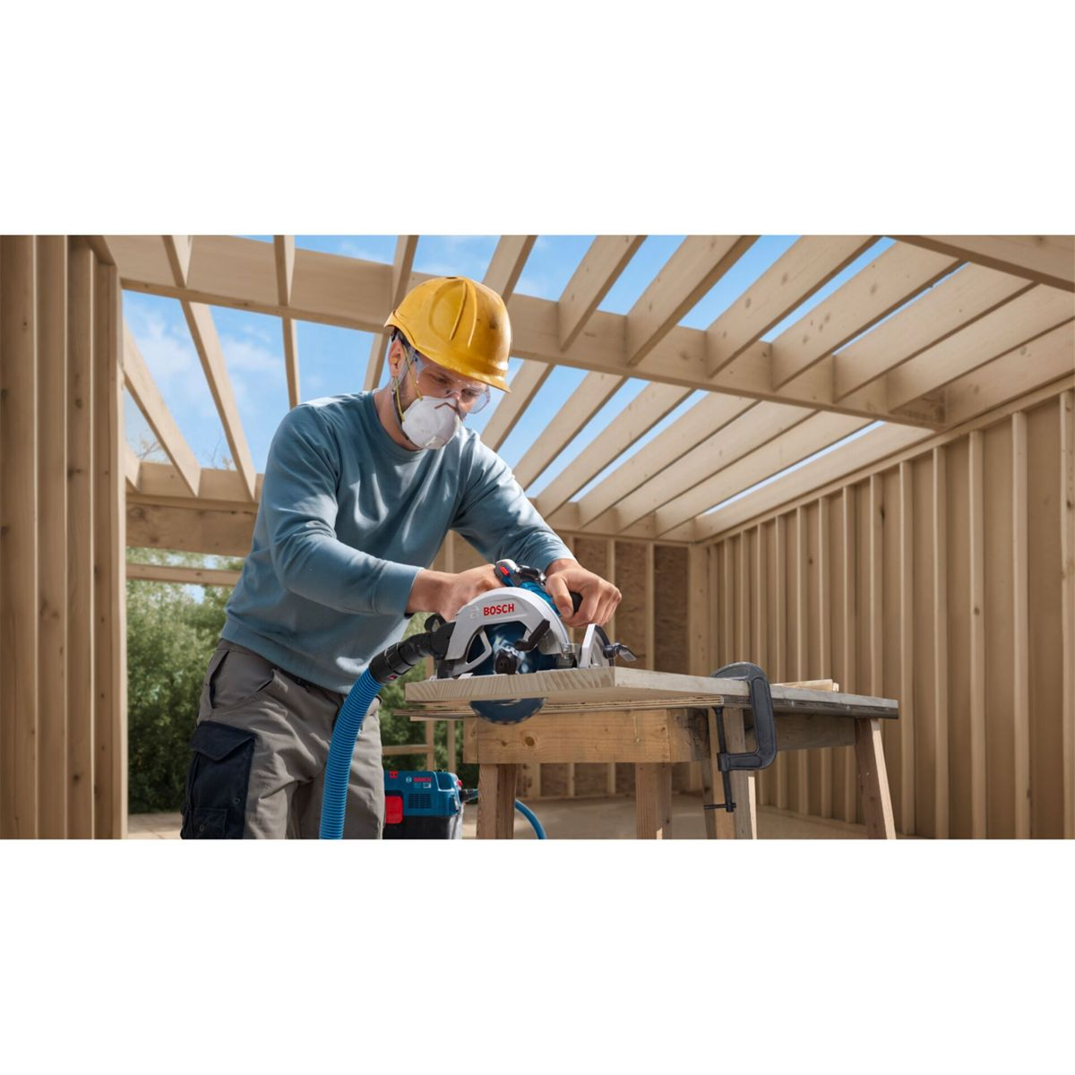 Man in veiligheidsuitrusting zaagt hout met cirkelzaag in houten constructie.