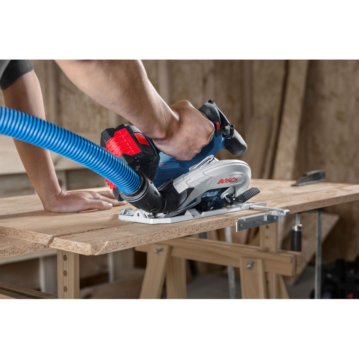 Man gebruikt een Bosch cirkelzaag met stofafzuiging op een houten plank.