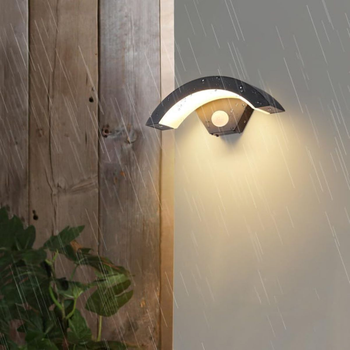 Moderne geschwungene schwarze Außenleuchte mit Bewegungssensor, beleuchtet im Regen.