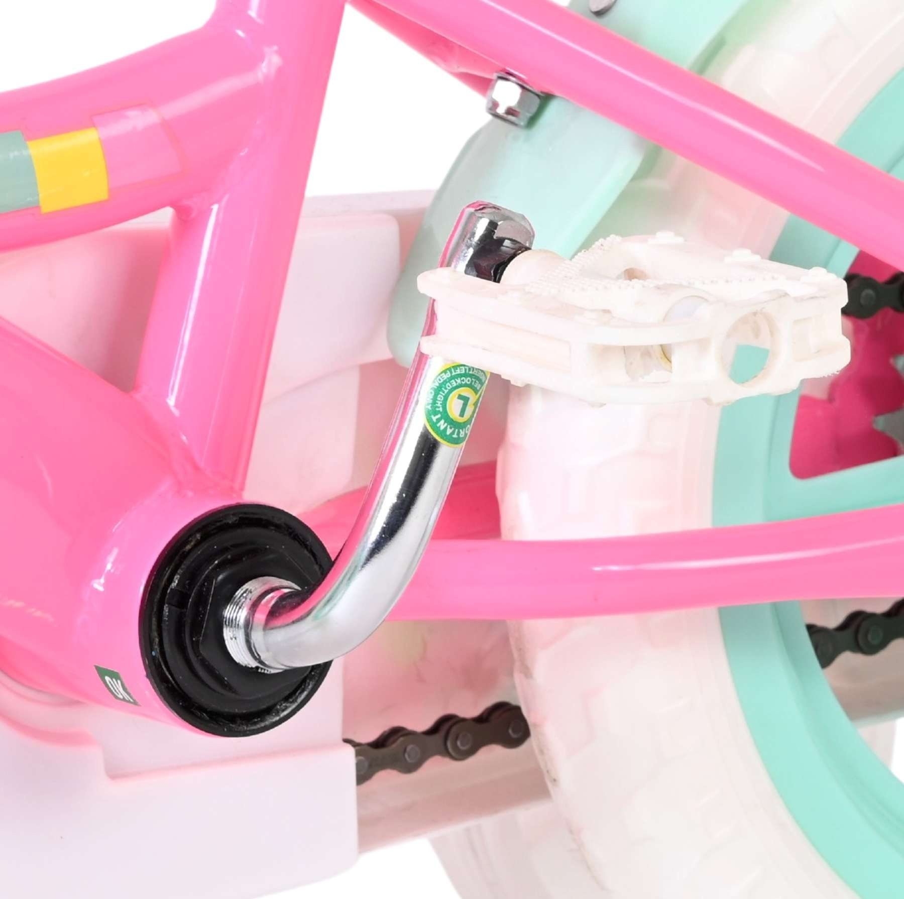Nahaufnahme der Kurbel, des weißen Pedals und der rosa Kette eines Kinderfahrrads.