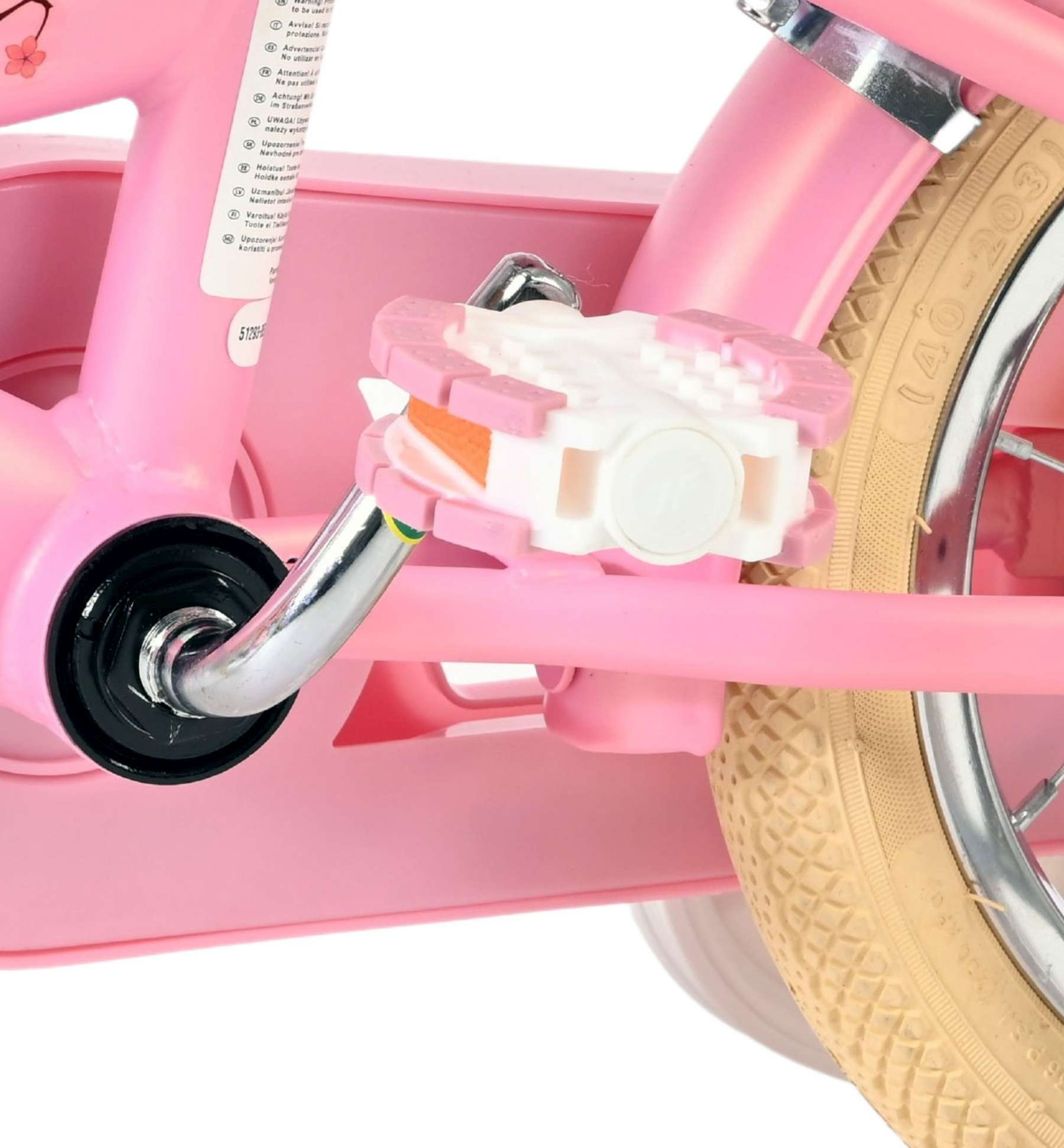 Nahaufnahme eines rosa Kinderfahrradpedals und Rades mit beigem Reifen.