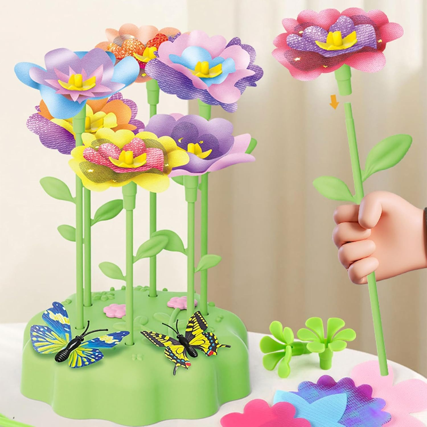 Eine Kinderhand montiert ein buntes Blumenspielzeug. Schmetterlinge schmücken die Basis.