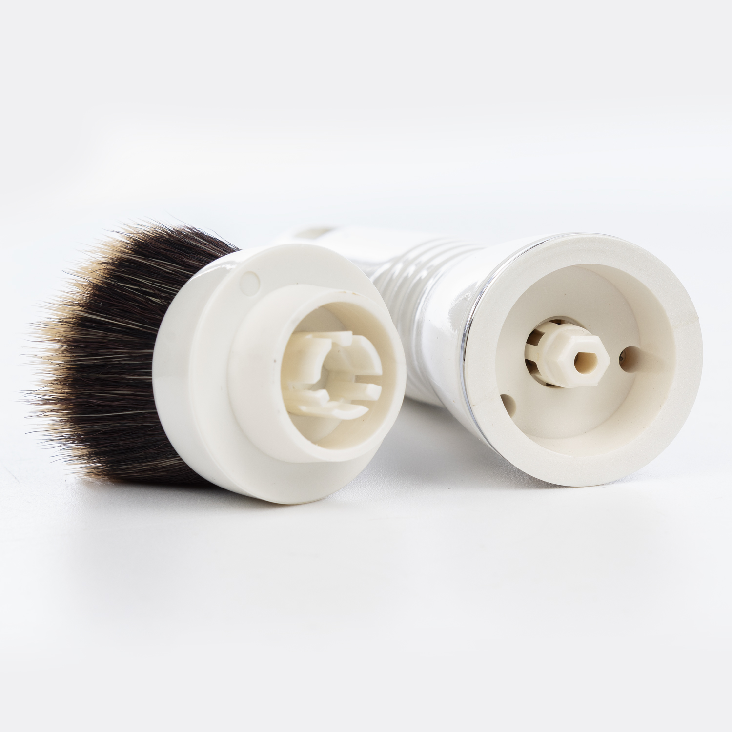 Un pennello da barba bianco con setole marroni e manico staccabile.