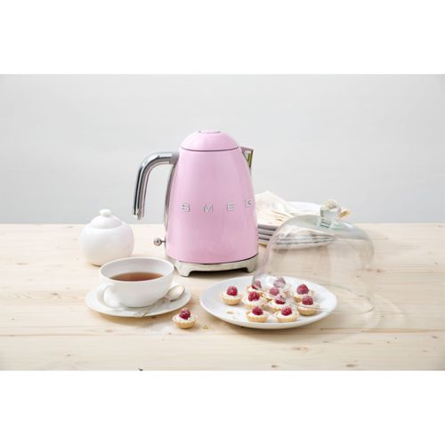 Een roze Smeg waterkoker staat naast een suikerpot en een kop thee.