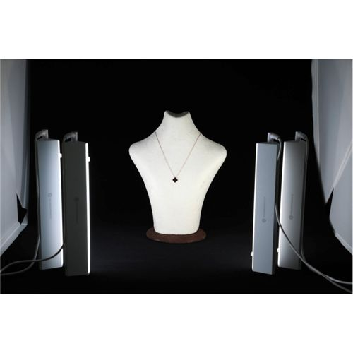 Weiße Schmuckbüste mit schwarzem Kleeblattanhänger-Halskette, beleuchtet von zwei Lichtern.