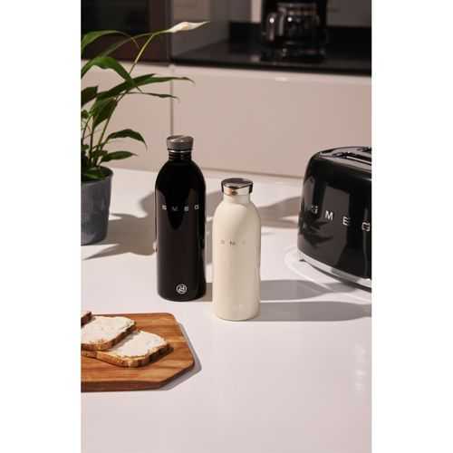 Siyah ve krem rengi Smeg su şişesi, tost ve tost makinesinin yanında tezgah üzerinde duruyor.