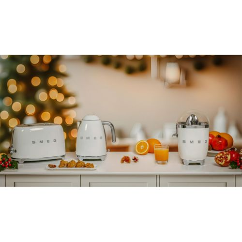Weiße Smeg-Geräte: Toaster, Wasserkocher, Entsafter. Orangen, Saft, Granatäpfel. Lichter.