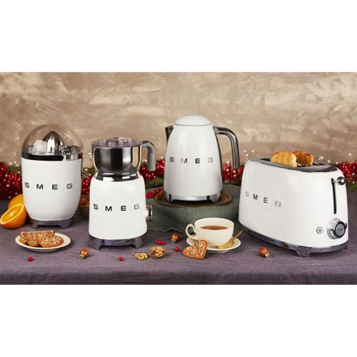 Weiße Smeg-Geräte: Entsafter, Mühle, Wasserkocher, Toaster. Mit Keksen, Orange und Tee.