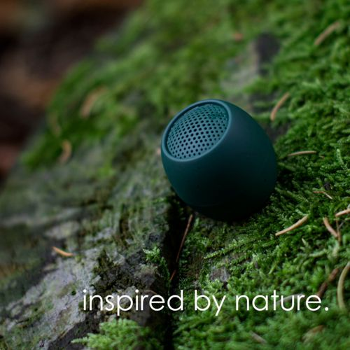 Ein kleiner, dunkelgrüner Lautsprecher auf moosigem Boden, mit Text 'inspired by nature.'