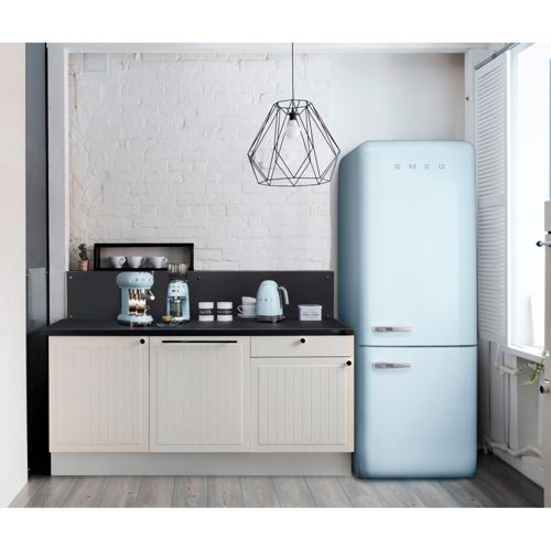 Ein hellblauer SMEG-Kühlschrank steht neben einer Küchenzeile mit Geräten.