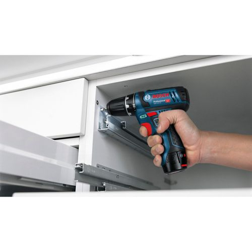 Een hand gebruikt een blauwe Bosch boormachine om een ladegeleider aan een kast te bevestigen.
