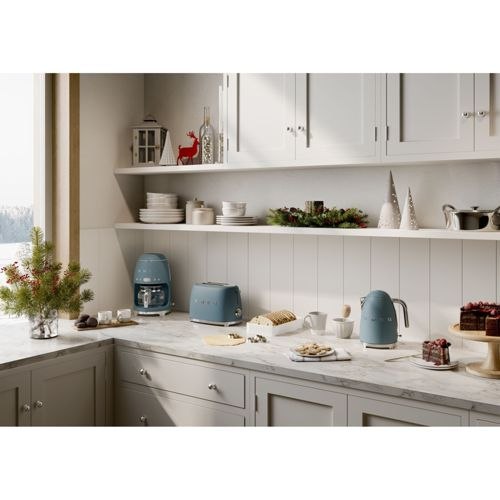 Una encimera de cocina azul con tostadora, cafetera y hervidor, decorada para invierno.