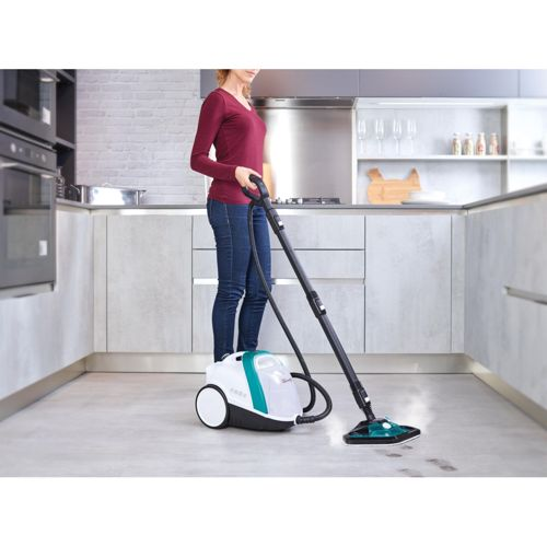 Una donna usa un pulitore a vapore per pulire il pavimento di una cucina moderna.